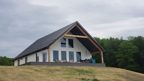 A modern house with a sloped roof, large windows, and a covered porch area.