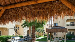 Un espacio de patio al aire libre con techo de paja, una estación de parilla y un pabellón.