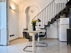 Eine moderne Küche mit Essbereich, einer Treppe und einem weißen Kühlschrank.