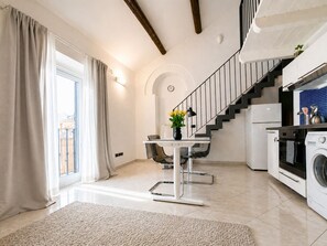 Eine moderne Küche mit Waschmaschine, ein Essbereich mit Tisch und Stühlen, eine Treppe und ein Blick ins Freie.