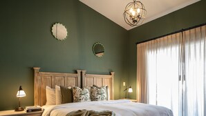 Un dormitorio con una cama grande, cabecera de madera, lámparas de noche, una mesita de noche y un banco.