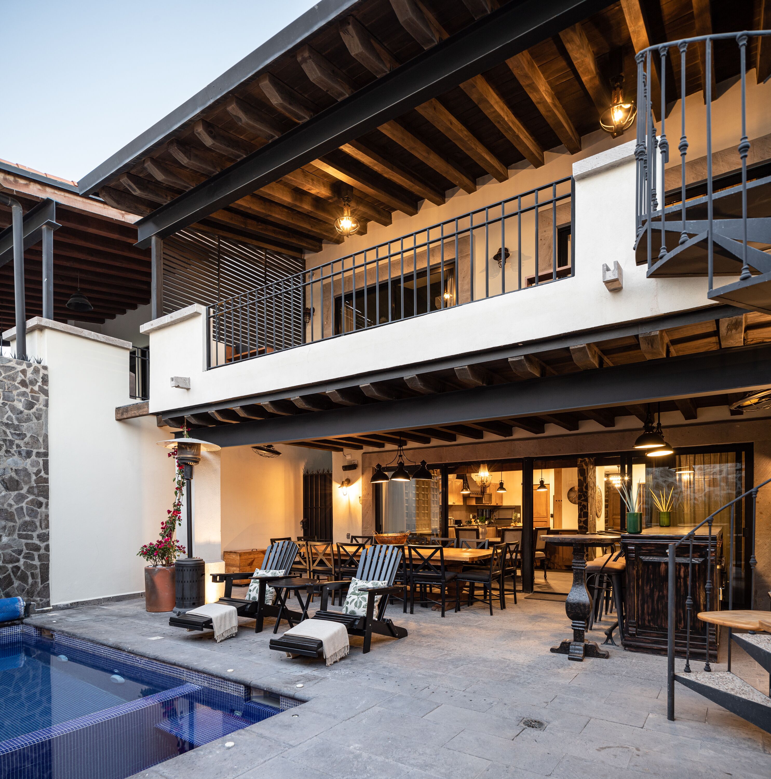 A two-story house with a balcony, outdoor seating area, and a swimming pool.