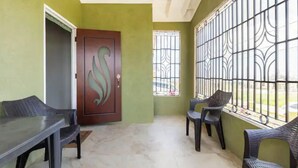 A room with a green wall, a wooden door with a decorative handle, a table, and two chairs. - New Quiet Gated Ocean View Home (Trelawny)
