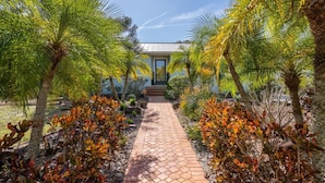 A pathway leading to a building surrounded by palm trees and colorful foliage.