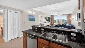 Een moderne keuken met een groot eiland, een roestvrijstalen spoelbak en een vaatwasser.