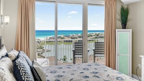 Een slaapkamer met een grote schuifdeur die uitkomt op een balkon met uitzicht op het strand en de oceaan.