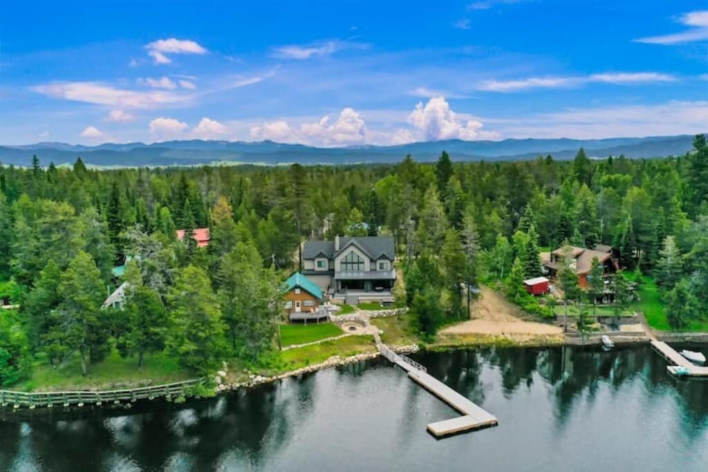 A lakeside property with a large house, dock, and surrounding forest.