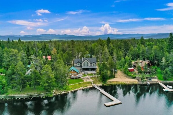 Una propiedad frente al lago con una casa grande, muelle y bosque circundante.