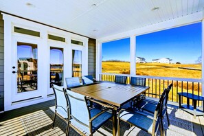 A covered patio with a table and chairs, large windows, and a view of a field. - Lakefront Luxury - NEW 6BR, Lake Anna, Dock, Games (Mineral)