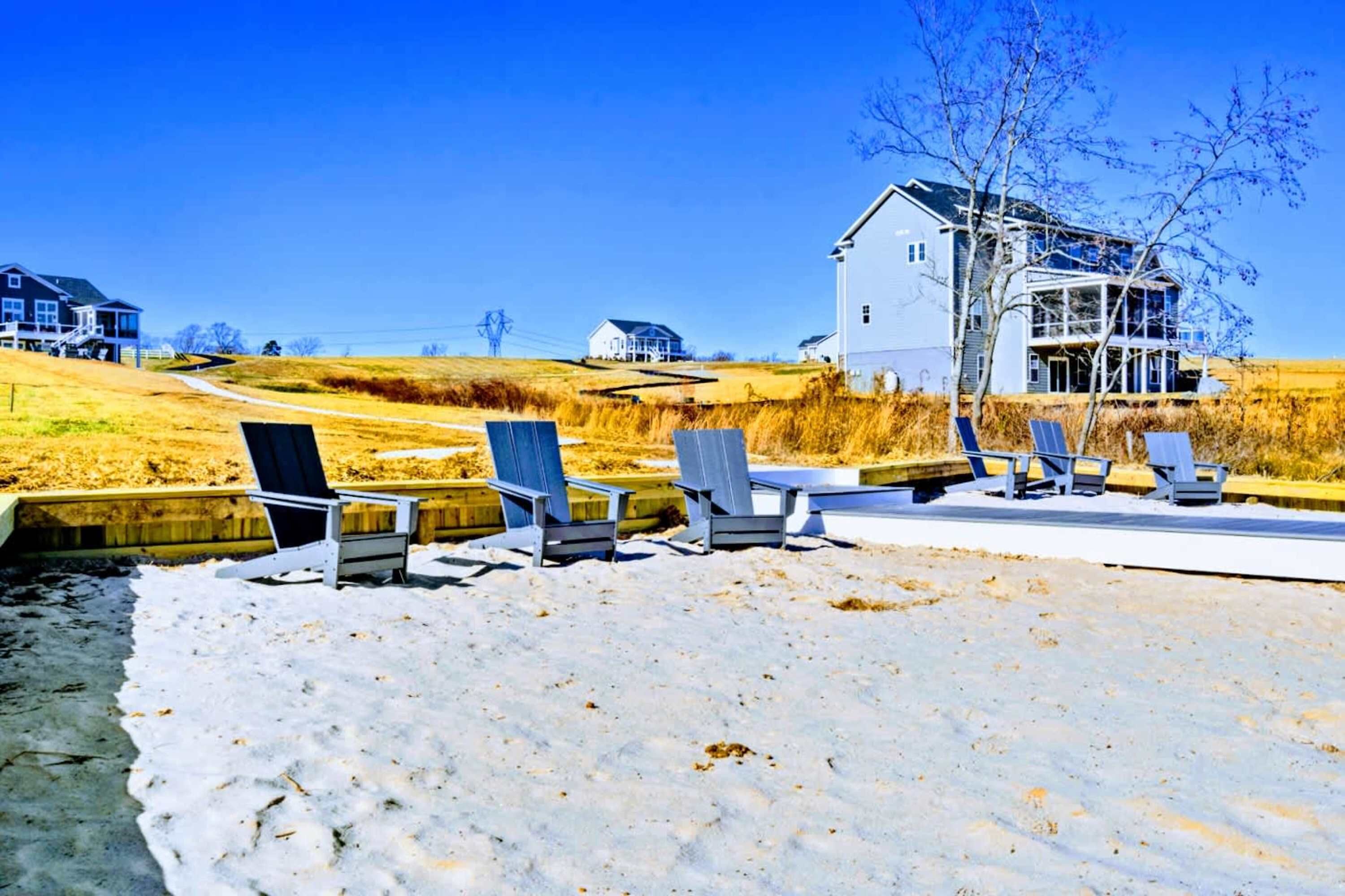 Une plage avec des chaises longues et une maison en arrière-plan.