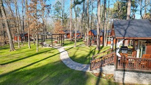 A lodge with outdoor seating, a stone pathway, and multiple cabins surrounded by trees.