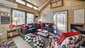Een knus interieur met houten plafond, een zwarte leren bank, een koffiebar en uitzicht op de natuur.