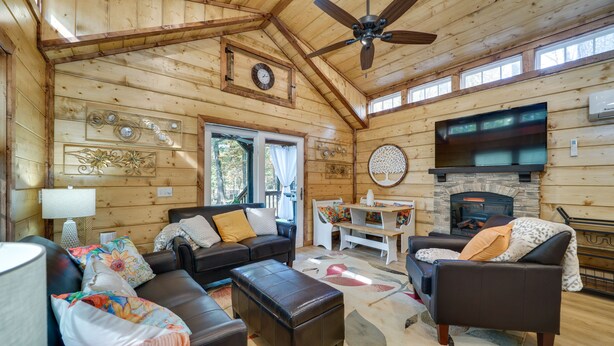 A cozy cabin interior with a fireplace, wooden walls, a ceiling fan, and a dining area. - Hook, Line, & Sinker Retreat: Fire Pit, Grill! (Broken Bow)