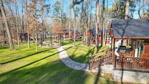 A lodge with outdoor seating, a stone pathway, and multiple cabins surrounded by trees. - Hook, Line, & Sinker Retreat: Fire Pit, Grill! (Broken Bow)