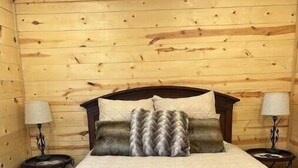 Een kamer met houten lambrisering, een bed, twee nachtkastjes en lampen.