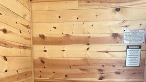 Een houten blokhut van binnen met een zwarte tafel en witte stoelen.
