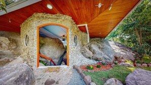 A rustic stone structure with a wooden ceiling and a door leading inside. - Artsy Riverfront Jungle Retreat: River Pool & Hot Tub in living room (Rivas)
