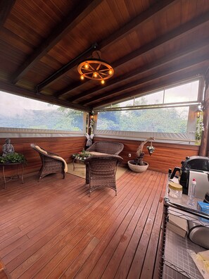 A wooden deck with wicker furniture, a Buddha statue, and a hanging light fixture.