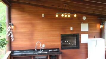 Una cabaña de madera con zona de cocina que incluye un lavamanos, encimera e iluminación colgante.
