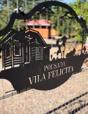 A sign with a silhouette of a house and horses, and the text 'POUSADA VILA FELICITA'.
