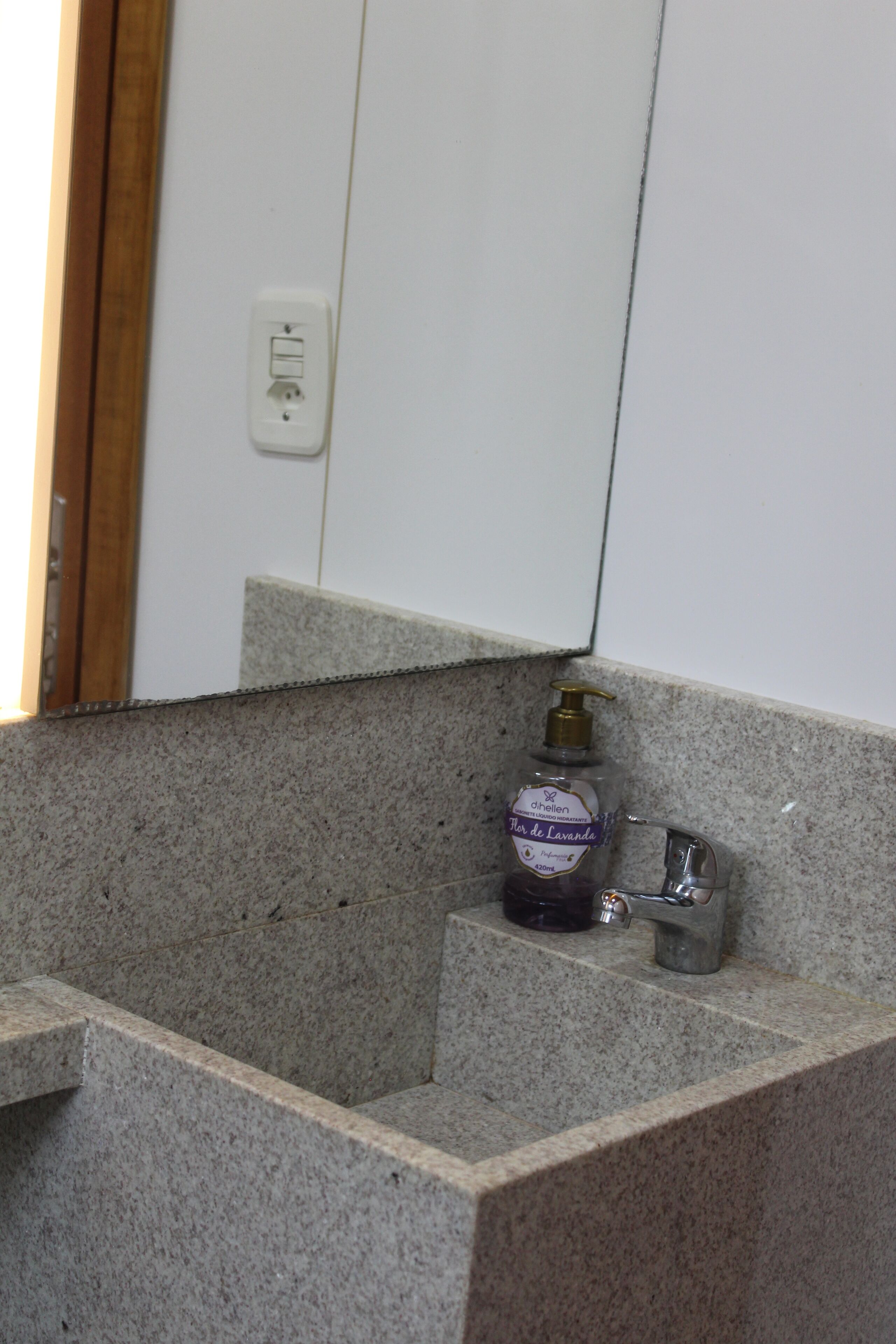 Baño con encimera de granito, dispensador de jabón y espejo.