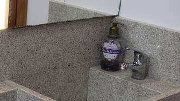 Baño con encimera de granito, dispensador de jabón y espejo.