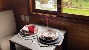 Ein Essbereich mit Tisch für zwei Personen, einem Fenster mit Blick auf Grünflächen und Berge sowie einer Holzvertäfelung.