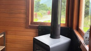 Ein Kaminofen in einem Zimmer mit Holzwänden und einem Fenster mit Blick auf einen Garten.