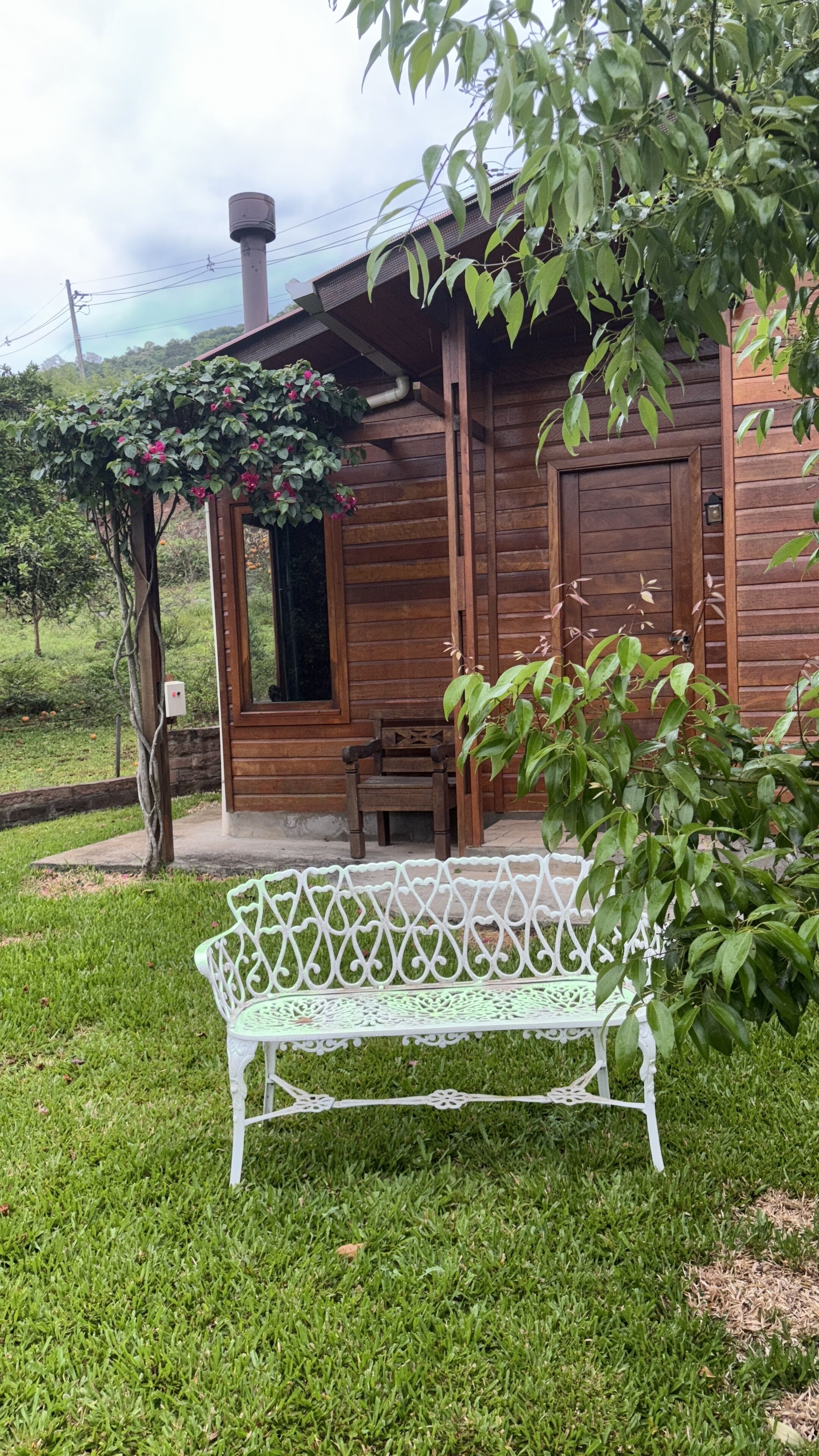 A wooden cabin with a porch, a bench, and a garden area.