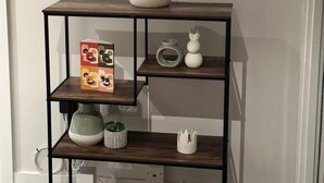 Une console en bois, surmontée d’un miroir, avec des étagères où sont disposés des objets décoratifs et un vase blanc.