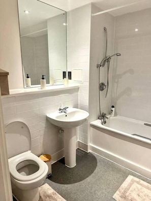 A modern bathroom with a toilet, sink, and bathtub. - Cosy, Comfy 2 Bed Apartment Canary Wharf (London)