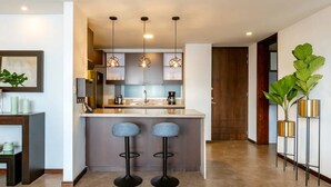 Una cocina moderna con una isla central, luces colgantes y taburetes de bar.
