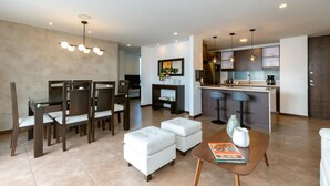 Una sala de estar moderna con comedor, cocina y una zona de estar con una mesa de centro.