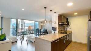 Una cocina moderna con una isla central, electrodomésticos de acero inoxidable e iluminación colgante.