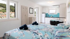 A bedroom with a bed, a small desk, and a view of a town through a window. - White Stone House - Four bedroom Holiday Home with Terrace (Pucisca)