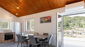 A modern kitchen with a dining area, large windows, and a view of a hillside town. - White Stone House - Four bedroom Holiday Home with Terrace (Pucisca)