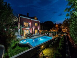 Una casa de dos pisos con piscina y zona de estar al aire libre.