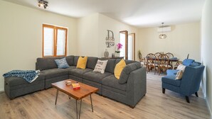 A living room with a sectional sofa, a wooden coffee table, and a dining area with a wooden table and chairs.