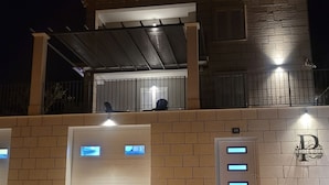 A building with a brick facade, a covered entrance, and illuminated garage doors.