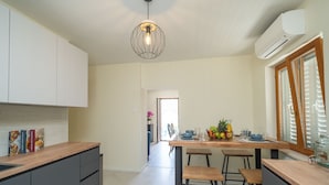 A modern kitchen with a central island, grey cabinets, and a hanging light fixture.
