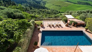 A swimming pool with a view of rolling hills and vineyards.