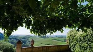 A stone wall with a lantern, overlooking a green valley with fields and distant hills.