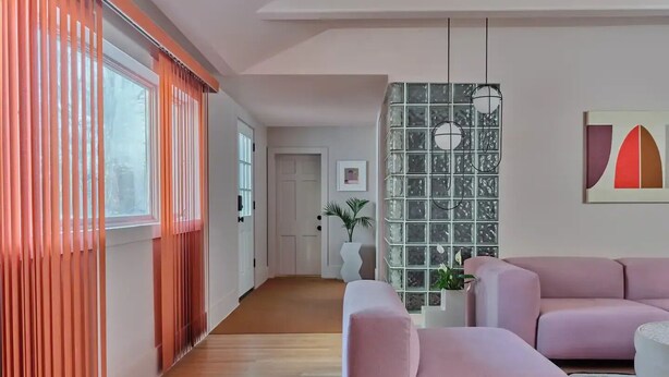 A modern living room with a pink sofa, a glass partition, and a minimalist decor.