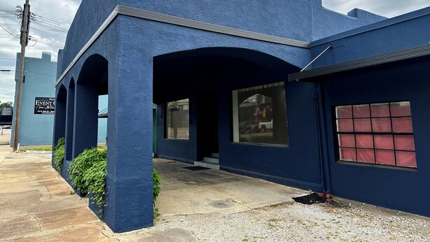 Un bâtiment à l’extérieur d’un bleu unique, doté de grandes fenêtres et d’une entrée bien visible.