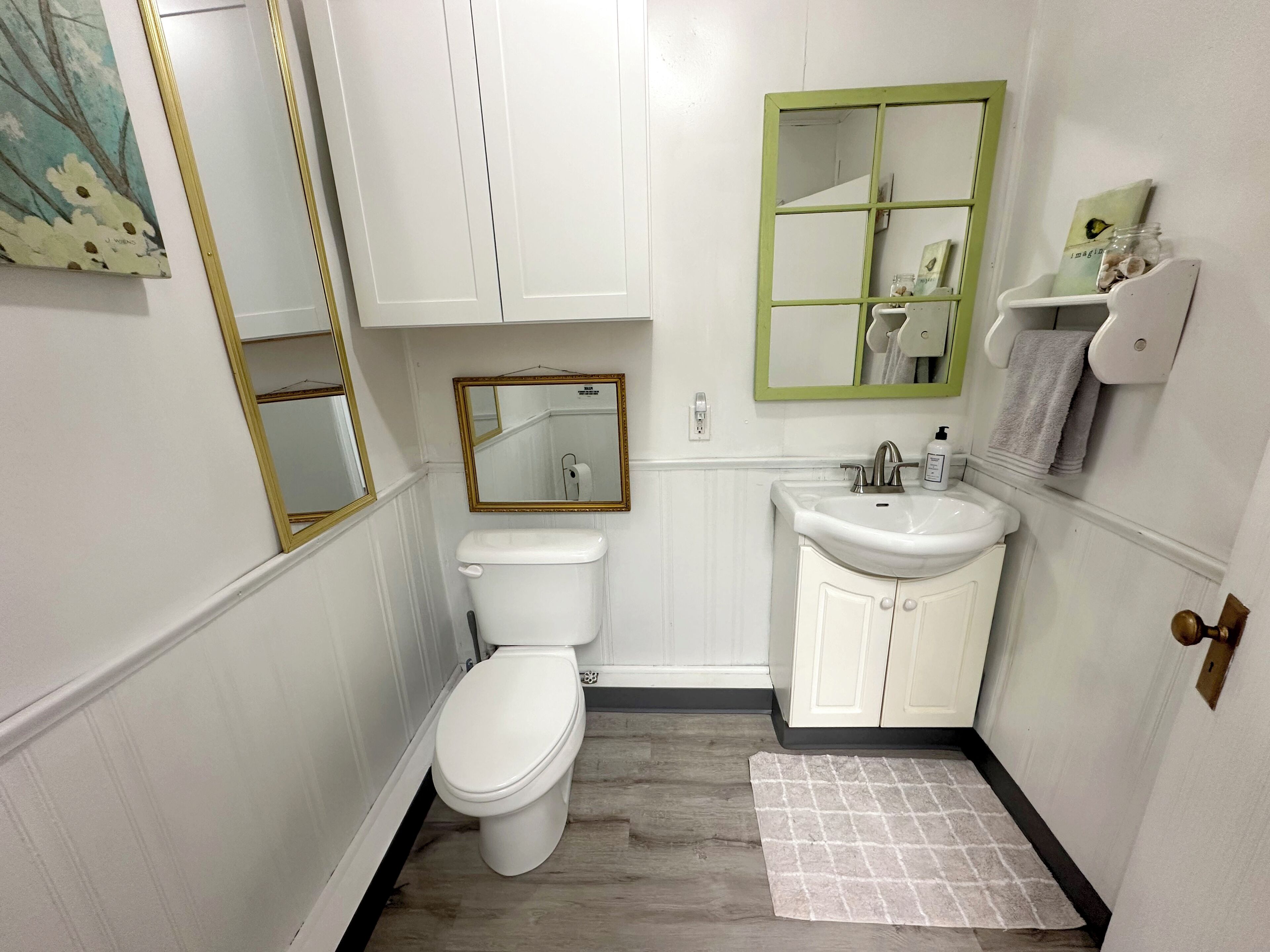 A compact bathroom with a toilet, sink, and mirror.