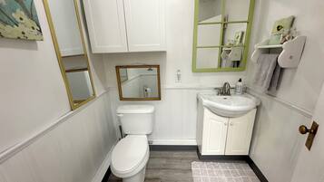 A compact bathroom with a toilet, sink, and mirror.