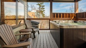 A wooden deck with two Adirondack chairs and a hot tub.