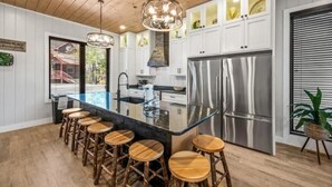 A modern kitchen with a central island, stainless steel appliances, and wooden bar stools.