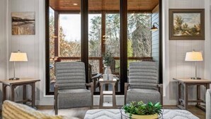 A room with two grey armchairs, a small table, and a potted plant.