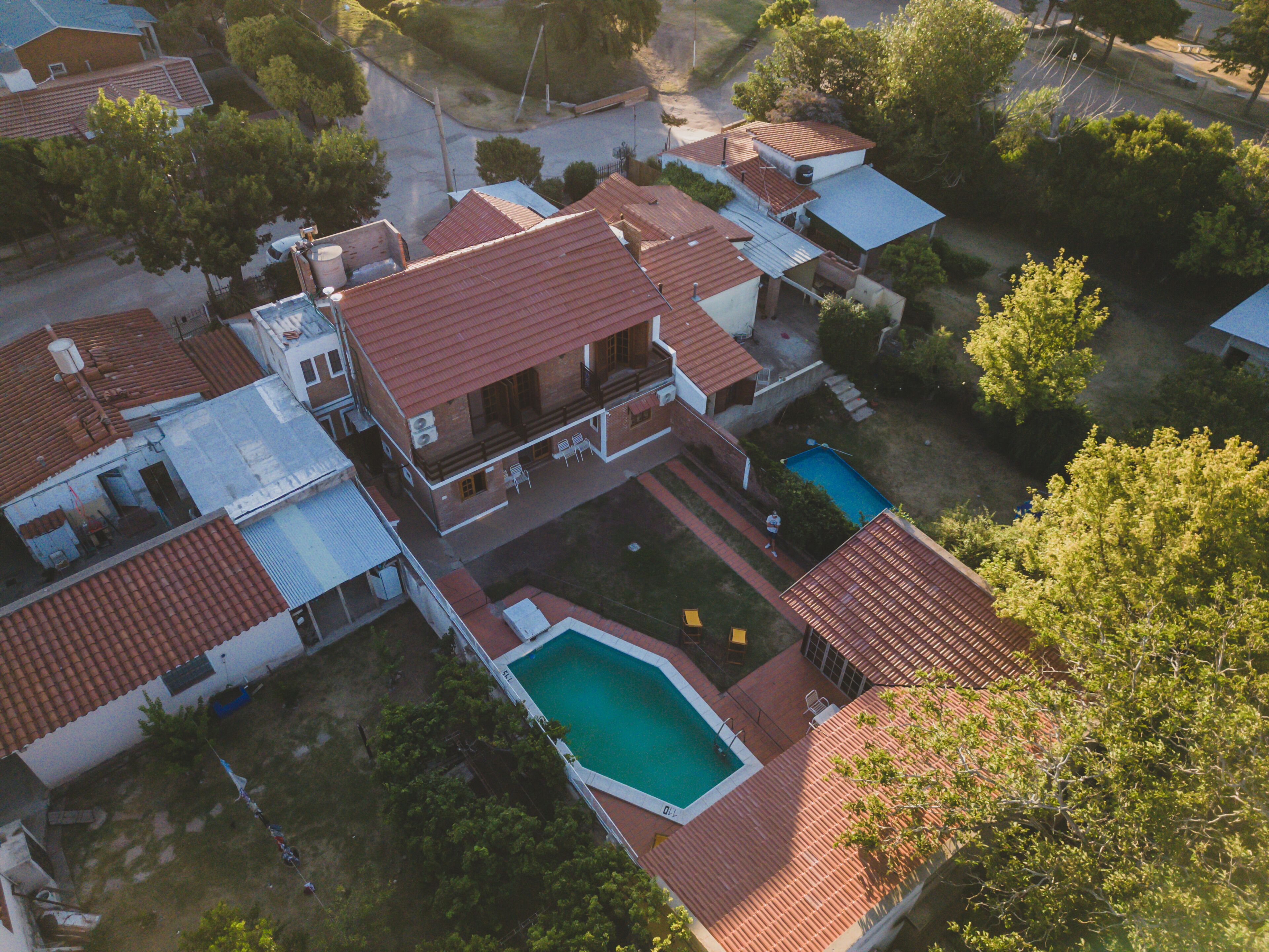 Vista aérea de una zona residencial con varias casas, una piscina y un pequeño jardín.